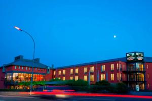 ein rotes Gebäude mit Straßenbeleuchtung davor in der Unterkunft Hotel Simon's Plaza in Grevenmacher