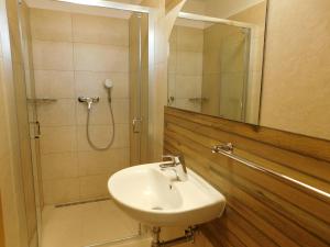 a bathroom with a sink and a shower with a mirror at Villa Petko in Vysoke Tatry - Dolny Smokovec