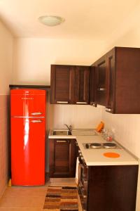 eine Küche mit einem roten Kühlschrank und Holzschränken in der Unterkunft Residence Le Casine in Batignano