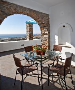 una mesa de cristal y sillas en un patio con vistas al océano en Grand View Tinos en Tinos Town