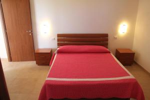 a bedroom with a bed with a red blanket at Residence Le Casine in Batignano