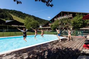 a group of people jumping into a swimming pool at Hôtel La Bergerie in Morzine