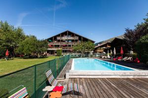 a swimming pool with two chairs next to a building at Hôtel La Bergerie in Morzine