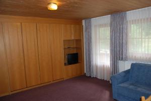 a living room with a blue chair and a tv at Appartment & Taxi Tirana in Samnaun