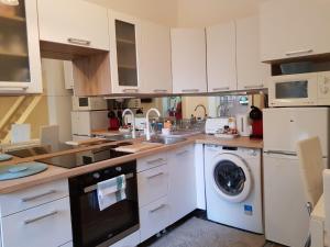 a kitchen with white cabinets and a washing machine at Brand New Garden Flat / Free Parking in Budapest