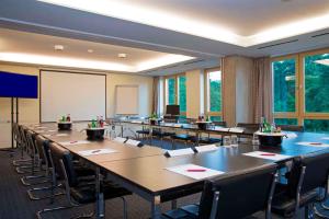 a conference room with tables and chairs and a whiteboard at Hotel Simon's Plaza in Grevenmacher