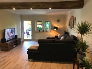 Ferienhaus Weinberg في فيرنيغيروده: غرفة معيشة مع أريكة سوداء وتلفزيون