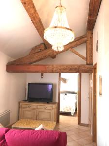 ein Wohnzimmer mit einem TV und einem Kronleuchter in der Unterkunft Studio du couvent in Narbonne