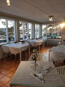 a restaurant with white tables and white chairs and windows at Pensar Hotelli & Ravintola Sandvik in Nauvo +116 photos