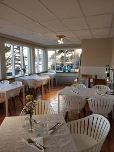 a restaurant with white tables and white chairs and windows at Pensar Hotelli & Ravintola Sandvik in Nauvo