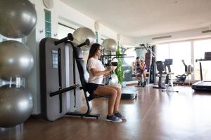 Una donna in palestra seduta su una macchina di Grand Hôtel Les Flamants Roses Thalasso & Spa a Canet-en-Roussillon