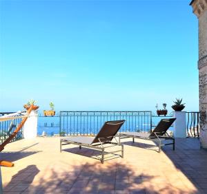 2 chaises assises sur une terrasse avec l'océan en arrière-plan dans l'établissement Villa Mundis Relais, à Massa Lubrense