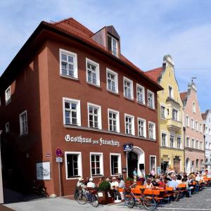 un grupo de personas sentadas en mesas fuera de un edificio en Hotel Freischütz Apartments, en Landshut
