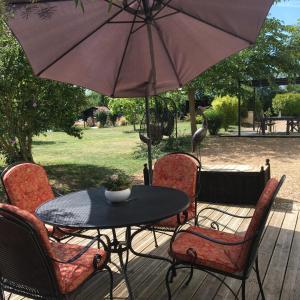 a table and chairs with an umbrella on a deck at La Chaumeauniere in Aigrefeuille-dʼAunis