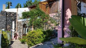 Una casa rosa con plantas a un lado. en Salina Acroeoliano monolocale panoramico, en Leni