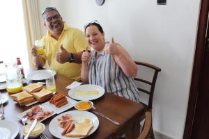Ein Mann und eine Frau sitzen am Tisch mit Frühstück in der Unterkunft Regal Rose Luxury Holiday Apartments in Nuwara Eliya