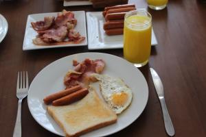 a table with two plates of breakfast food and orange juice at Regal Rose Luxury Holiday Apartments in Nuwara Eliya