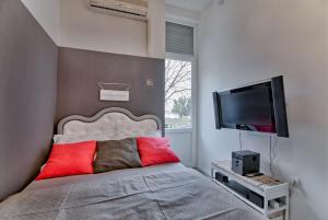 Schlafzimmer mit einem Bett mit roten Kissen und einem Flachbild-TV in der Unterkunft Luxury with sea view in Pula