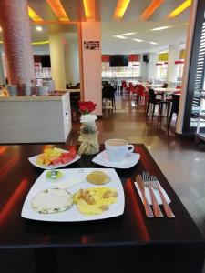 a table with two plates of food and a cup of coffee at Hotel Grand Premium Plaza in Pitalito