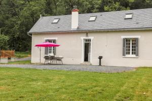 a white house with a table and a pink umbrella at Country House - La Valentrée in Continvoir