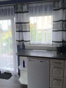 a kitchen with a sink and two windows with curtains at VIP Appartement in Mahlberg