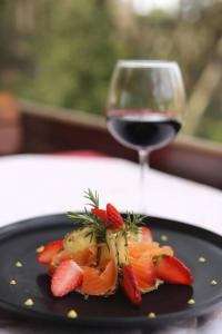a black plate with strawberries and a glass of wine at Hotel Restaurant Dreri in Tirana
