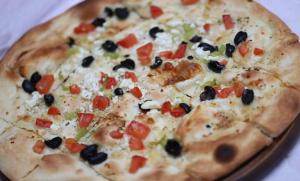 a pizza with olives and tomatoes on a table at Hotel Restaurant Dreri in Tirana