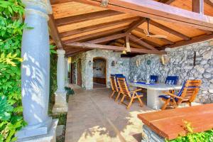 patio ze stołem i krzesłami oraz kamienną ścianą w obiekcie Villa Baronessa w mieście Lovran