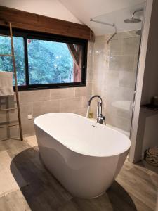 a large white bath tub in a bathroom with a window at Villa Rustique Le Carriou in Léon