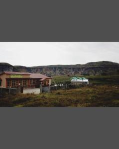 un edificio en un campo con montañas en el fondo en Nalgre Homestay, en Cherrapunji