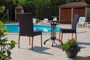 duas cadeiras e uma mesa em frente a uma piscina em Hotel du Commerce Chez Stéphane em Roumazières