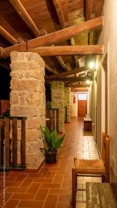 a hallway with a stone wall and a wooden ceiling at Agriturismo Costiolu in Nuoro