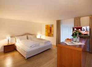 a bedroom with a bed and a table with flowers on it at Hotel Taverne zum Kreuz in Olten