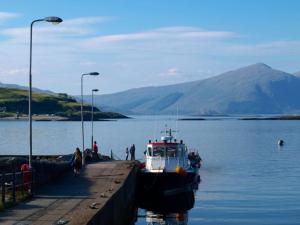 a boat is docked at a dock in the water at Coachmans Bothy - 50m from the beach in Port Appin