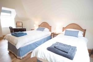 een slaapkamer met 2 bedden en handdoeken bij Coachmans Bothy - 50m from the beach in Port Appin