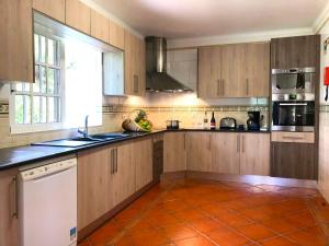 cocina con armarios de madera y suelo de baldosa naranja en Villa Tenazinha III, en Albufeira