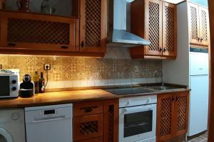 a kitchen with wooden cabinets and a white stove top oven at Casa Balcón de Albarracín in Albarracín
