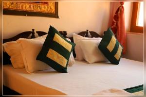 Una cama con cuatro almohadas encima. en Hotel Renuka, en Jaisalmer