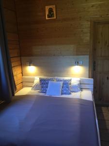 a large bed in a wooden room with two lights at Economy rooms for 2-4 people in Anykščiai