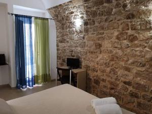 a bedroom with a stone wall with a bed and a desk at La Corte Di Ibla in Ragusa