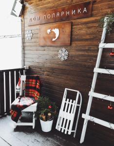 a porch with a ladder and a chair and a sign at Guesthouse Husky Moa in Poselok-Matrosy