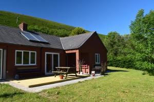 a house with a deck and a picnic table at Healing Pastures Farm in Llanbrynmair