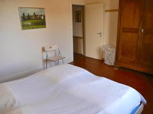 a bedroom with a white bed and a chair at vakantiehuis Morvan in Dun-sur-Grandry