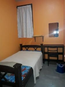 1 dormitorio con 2 camas, ventana y silla en Hotel Latino, en San José