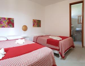 two beds in a room with red and white sheets at Paranambuca Pousada in Porto De Galinhas