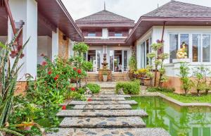 a house with a pond in the front yard at Thai style villa with very beautiful private pool in Kamala Beach