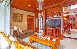 a living room with a couch and a tv at Thai style villa with very beautiful private pool in Kamala Beach