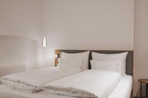 Cama blanca con sábanas y almohadas blancas en Kuntino Suites en Merano