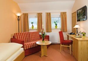 a hotel room with a couch and a table at Brammers Landhotel Zum Wietzetal in Wietzendorf