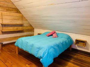 a bed that has a blue blanket on it at Casa Apel Hostel in Puerto Varas